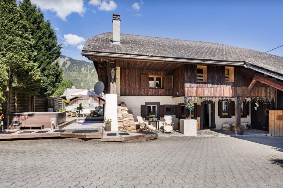 The charming exterior of Chalet La Fourmiliere, taken from the car park, showing a hot tub terrace on the left and the chalet itself.