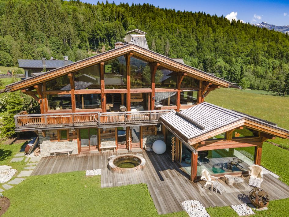 External of Chalet des Cristaux, with the outdoor hot tub, spacious balcony and forest surroundings.