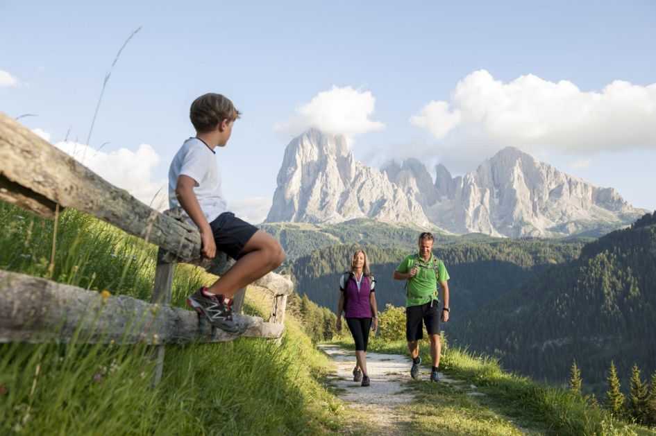 Child waiting for his parents on the fence, whilst on the Sellaronda Hike Tour - one of the best hikes in the mountains that needs to be added to your luxury walking holidays in Europe!