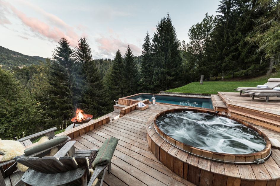 External of Ferme de Moudon, showing the outdoor hot tub, swimming pool and wonderful forest views. One of the best places to relax on a self catered summer mountain holiday.