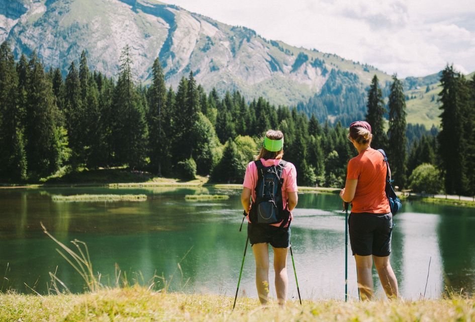 Two walkers look out across Lac de Montriond, a stunning green lake near Morzine