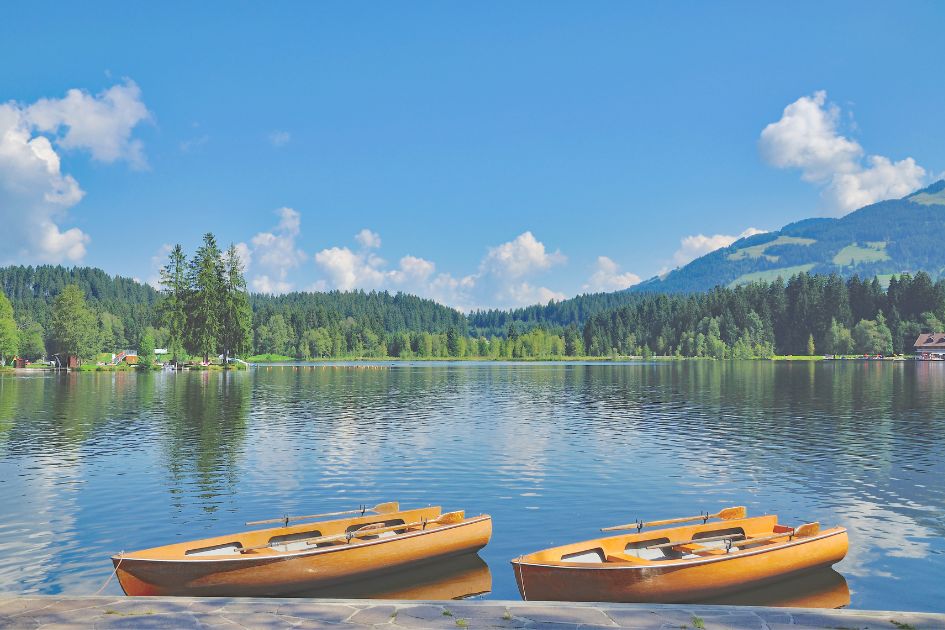 Rowing boats on the beautiful Lake Schwarzsee in Kitzbühel. Views across rolling hills and green trees.