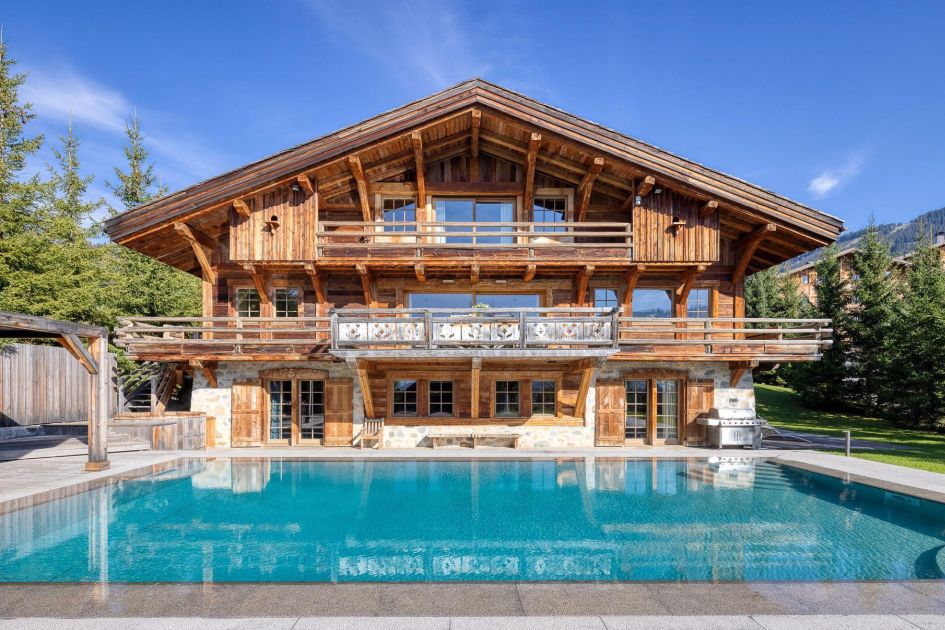 Chalet Izoard's wooden exterior with swimming pool in front. As one of the best properties in the Alps, it's perfect for booking your summer chalet holiday in 2025 early!