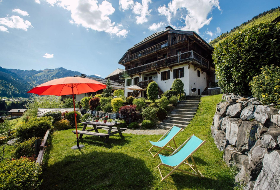 Chalet Debussy exterior, with an umbrella beside the picnic table and loungers facing the sun in the garden.