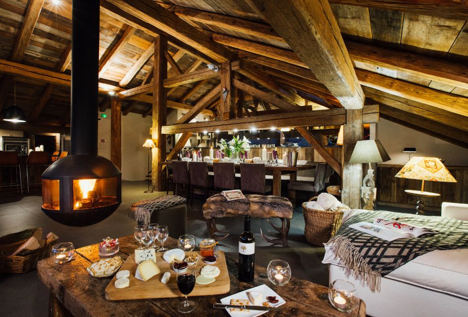 Interior of Chalet Debussy, an eco-conscious summer mountain chalet in Morzine. Showcasing the floating fireplace, bar area, and a cheeseboard with wine.